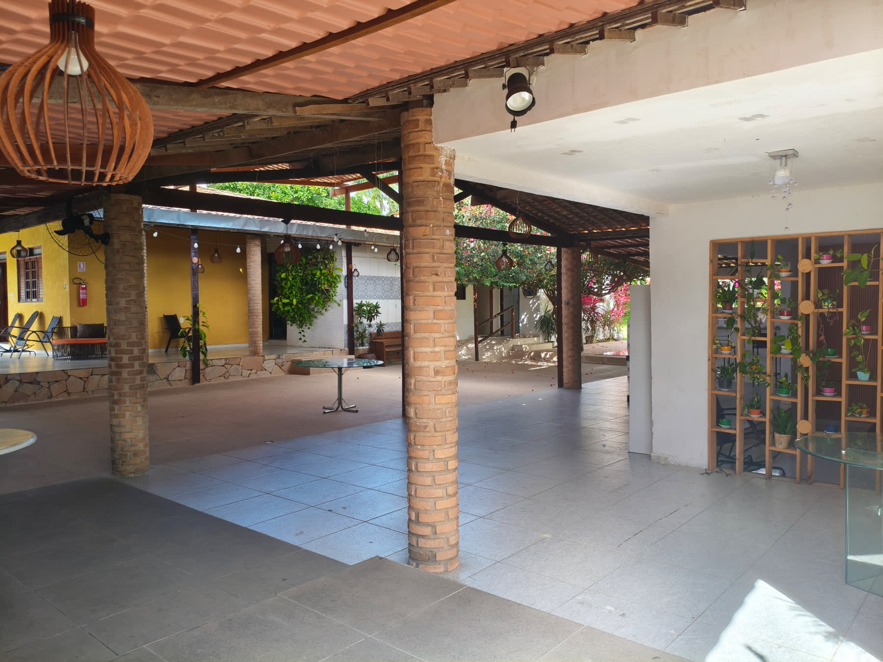 Pátio coberto do Studio29 com pilares de tijolo, telhado de madeira e áreas de estar
